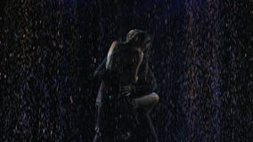 A passionate Latin American bachata dance performed by a lovely couple. Silhouettes in drops of rain on a black
