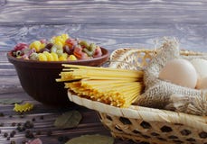 Pasta av olika färger, spagetti, tre ägg, svartpeppar och lagerbladen på en mörk bakgrund och bambukorg arkivbilder Pasta av olika färger, spagetti, tre ägg, svartpeppar och lagerbladen på en mörk bakgrund och bambukorg arkivbilder