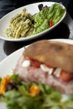 Pastamaträtt med grön Pesto och sallad på en vit platta royaltyfri foto Pastamaträtt med grön Pesto och sallad på en vit platta royaltyfri foto