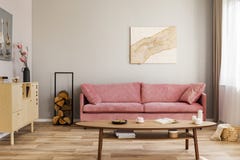 Pastel abstract painting on beige wall behind velvet pink settee in simple living room