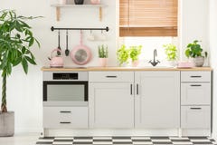 Pastelkleur roze pan en ketel in een mooi keukenbinnenland met eenvoudige, witte kasten en gootsteen door het venster met zonnebl stock foto's Pastelkleur roze pan en ketel in een mooi keukenbinnenland met eenvoudige, witte kasten en gootsteen door het venster met zonnebl stock foto's