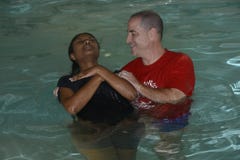 A pastor is baptizing a female during a church baptismal event