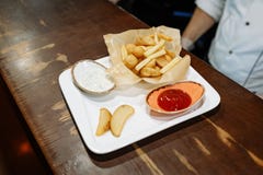 Patatas fritas y bolas de la patata con el tomate y la salsa blanca en una placa blanca en una tabla de madera fotografía de archivo libre de regalías Patatas fritas y bolas de la patata con el tomate y la salsa blanca en una placa blanca en una tabla de madera fotografía de archivo libre de regalías