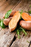 Patate douce sur le fond en bois avec Rosemary et Basil frais image libre de droits Patate douce sur le fond en bois avec Rosemary et Basil frais image libre de droits