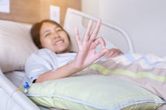 Patient asian woman showing hands ok sign on sick bed at the hospital,Health insurance concept