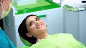 Patient féminin satisfaisant souriant après examen dentaire régulier de cavité buccale image libre de droits Patient féminin satisfaisant souriant après examen dentaire régulier de cavité buccale image libre de droits