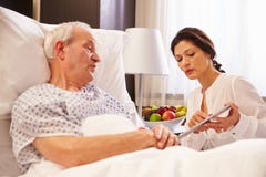 Patient masculin féminin de docteur Talking To Senior dans le lit d'hôpital images libres de droits Patient masculin féminin de docteur Talking To Senior dans le lit d'hôpital images libres de droits