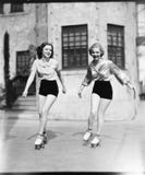 Patinaje sobre ruedas de dos mujeres jovenes en el camino y sonrisa (todas las personas representadas no son vivas más largo y ni foto de archivo libre de regalías Patinaje sobre ruedas de dos mujeres jovenes en el camino y sonrisa (todas las personas representadas no son vivas más largo y ni foto de archivo libre de regalías