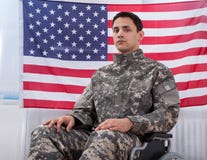 Patriotic soldier sitting on wheel chair against american flag stock images Patriotic soldier sitting on wheel chair against american flag stock images
