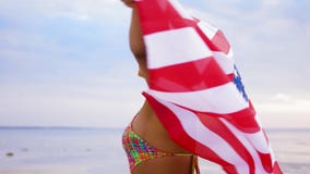 Happy african woman with american flag on beach stock video Happy african woman with american flag on beach stock video