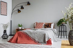 Patterned pillow and grey blanket on king size bed with dark orange duvet in luxury bedroom interior in elegant apartment