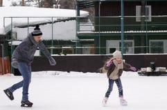 Pattino della figlia e di papà sulla pista di pattinaggio sotto il cielo aperto un giorno di inverno fotografia stock libera da diritti Pattino della figlia e di papà sulla pista di pattinaggio sotto il cielo aperto un giorno di inverno fotografia stock libera da diritti