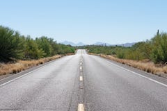Paved road ahead through the desert with mountains in the background royalty free stock photography Paved road ahead through the desert with mountains in the background royalty free stock photography