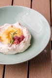 Pavlova mini cake with custard cream and fresh summer berries on green plate on wooden background. Baked meringue cake. stock photos Pavlova mini cake with custard cream and fresh summer berries on green plate on wooden background. Baked meringue cake. stock photos