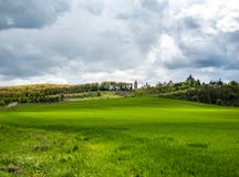 Paysage attirant avec l'herbe verte de ressort, les collines et les arbres, ciel nuageux images stock Paysage attirant avec l'herbe verte de ressort, les collines et les arbres, ciel nuageux images stock