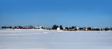 Paysage rural avec un village sur l'horizon après champ de neige sous le ciel sans nuages bleu clair sur la vue panoramique lumin photo stock Paysage rural avec un village sur l'horizon après champ de neige sous le ciel sans nuages bleu clair sur la vue panoramique lumin photo stock