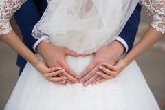 Państwo młodzi trzyma ich ręki w kierowym kształcie Fotografia Stock Państwo młodzi trzyma ich ręki w kierowym kształcie Fotografia Stock