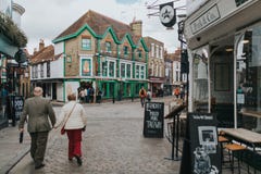 Pedestrian walking along cobblestoned street, with shops around it, and traditional architecture in the village of Canterbury, stock photo Pedestrian walking along cobblestoned street, with shops around it, and traditional architecture in the village of Canterbury, stock photo
