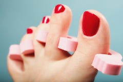 Pedicura del pie que aplica las uñas del pie rojas en azul Fotos de archivo libres de regalías Pedicura del pie que aplica las uñas del pie rojas en azul Fotos de archivo libres de regalías