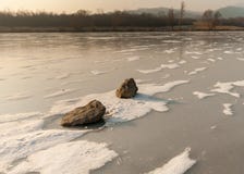 Pedras que encontram-se no rio congelado com os pontos da neve fraca imagens de stock Pedras que encontram-se no rio congelado com os pontos da neve fraca imagens de stock