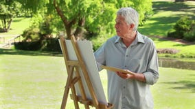 Peinture mûre sérieuse d'homme sur une toile clips vidéos Peinture mûre sérieuse d'homme sur une toile clips vidéos