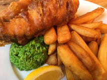 Peixe com batatas fritas golpeado, com sopa de ervilhas imagem de stock Peixe com batatas fritas golpeado, com sopa de ervilhas imagem de stock
