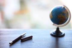 A pen on the desk and a small globe