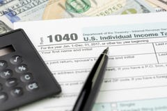Pen on 1040 US individual income tax filling form with black calculator and US dollar bill, tax submission or revenue calculation royalty free stock images Pen on 1040 US individual income tax filling form with black calculator and US dollar bill, tax submission or revenue calculation royalty free stock images