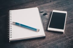 Pencil On A Blank Notebook Lying Next To A Business Smartphone On An Old Table. A Pencil On A Blank Notebook Lying Next To A Business Smartphone On An Old Table Stock Photo Pencil On A Blank Notebook Lying Next To A Business Smartphone On An Old Table. A Pencil On A Blank Notebook Lying Next To A Business Smartphone On An Old Table Stock Photo