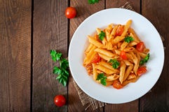 Penne pasta in tomato sauce with chicken, tomatoes decorated with parsley