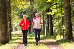 Pensionärer som joggar på en skogväg Arkivfoton Pensionärer som joggar på en skogväg Arkivfoton