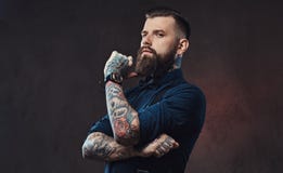 Pensive handsome old-fashioned hipster in a blue shirt and suspenders, standing with hand on chin in a studio. Royalty Free Stock Photography Pensive handsome old-fashioned hipster in a blue shirt and suspenders, standing with hand on chin in a studio. Royalty Free Stock Photography