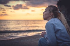 Pensive lonely smiling woman looking with hope into horizon during sunset at beach stock image Pensive lonely smiling woman looking with hope into horizon during sunset at beach stock image