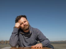 Pensive man with a beard and mustache sitting at a coffee table against a blue sky royalty free stock photos Pensive man with a beard and mustache sitting at a coffee table against a blue sky royalty free stock photos
