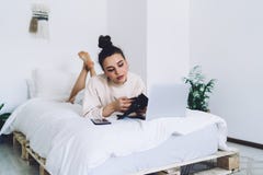 Pensive woman checking wallet while relaxing in bed