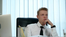 A pensive young man sitting in his office at work stock footage A pensive young man sitting in his office at work stock footage