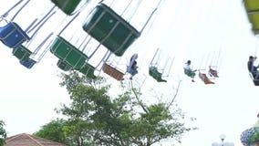 People riding on chain carousel attraction in amusement park. Happy friends having fun on colorful carousel in amusement