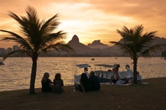 People sitting between palm trees in front of the lake and watch sunset stock photography People sitting between palm trees in front of the lake and watch sunset stock photography
