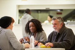 People Sitting At Table Eating Food In Homeless Shelter royalty free stock photography People Sitting At Table Eating Food In Homeless Shelter royalty free stock photography