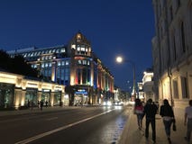 People walk in the evening summer streets of Moscow. Illuminated building of the store `Detsky mir stock photography People walk in the evening summer streets of Moscow. Illuminated building of the store `Detsky mir stock photography
