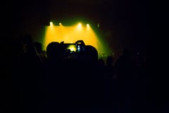 People watching a concert and someone shooting photo and video with a cellphone royalty free stock photography People watching a concert and someone shooting photo and video with a cellphone royalty free stock photography