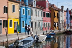 2 people walking - Houses of Burano and reflection in the water. Waterways with traditional boats and colorful facade. Venice - It stock image 2 people walking - Houses of Burano and reflection in the water. Waterways with traditional boats and colorful facade. Venice - It stock image