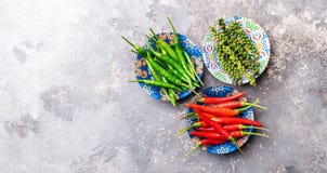 Peppers of various types of red green black in a bowl with colorful ornaments on a gray background. Flat layout. royalty free stock photography Peppers of various types of red green black in a bowl with colorful ornaments on a gray background. Flat layout. royalty free stock photography