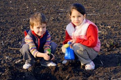 Pequeños niños en el campo que siembra la planta fotografía de archivo libre de regalías Pequeños niños en el campo que siembra la planta fotografía de archivo libre de regalías