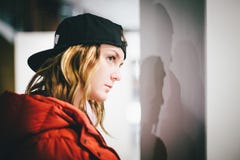 Perfil de la cara de la muchacha de moda en la chaqueta roja que lleva el casquillo elegante foto de archivo libre de regalías Perfil de la cara de la muchacha de moda en la chaqueta roja que lleva el casquillo elegante foto de archivo libre de regalías