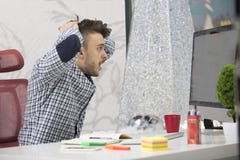 Perfil lateral disparado de empresário triguenho novo frustrante, gritando em seu portátil no escritório e nos grampos os origina foto de stock Perfil lateral disparado de empresário triguenho novo frustrante, gritando em seu portátil no escritório e nos grampos os origina foto de stock