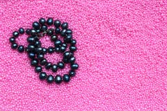 Perle nere della perla su fondo rosa, spazio della copia fotografia stock Perle nere della perla su fondo rosa, spazio della copia fotografia stock