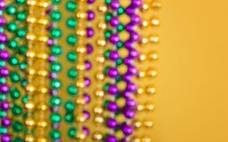 Perles Defocused de Mardi Gras sur le fond jaune photo stock Perles Defocused de Mardi Gras sur le fond jaune photo stock