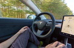 Person driving a new Tesla Model 3 in autopilot mode. stock photo Person driving a new Tesla Model 3 in autopilot mode. stock photo