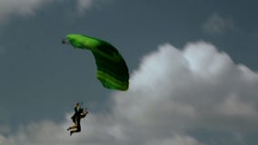 A person on the green parachute is about to land